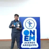 Albert muestra una medalla junto a un panel de ONEM Aceros Arequipa.