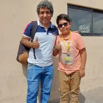Albert lleva medallas y una credencial mientras posa junto a otra persona al aire libre.