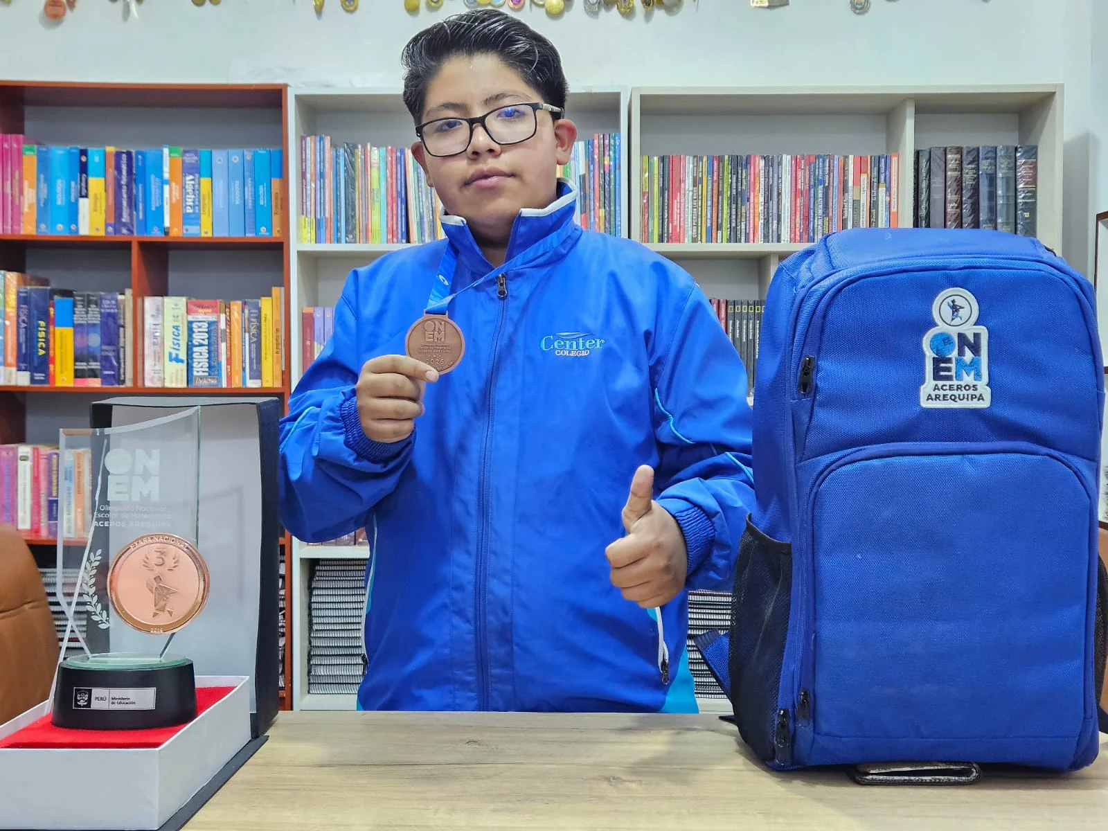 Albert con uniforme azul, una medalla y su mochila de competencia.